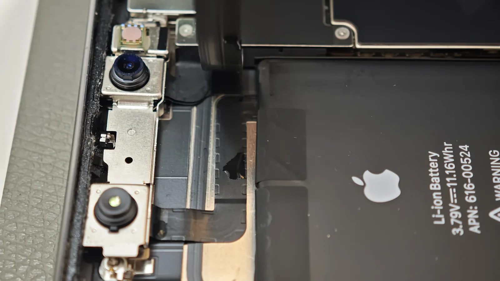 Reziduu de lichid lângă baterie și camerele unui iPhone XR
