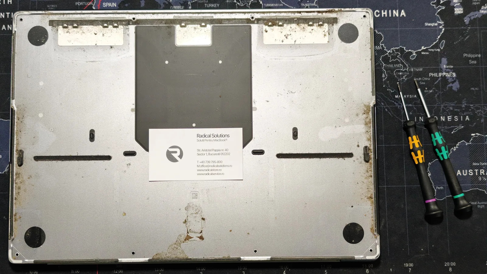 Capacul de jos al MacBook Pro 16, cu urme de lichid și depuneri de pământ