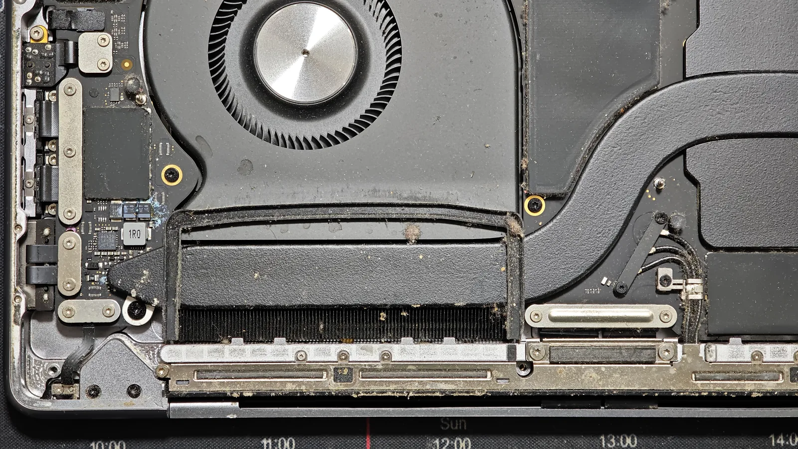 Radiatorul MacBook Pro 16 plin de praf și pământ, cu urme de coroziune lângă componente